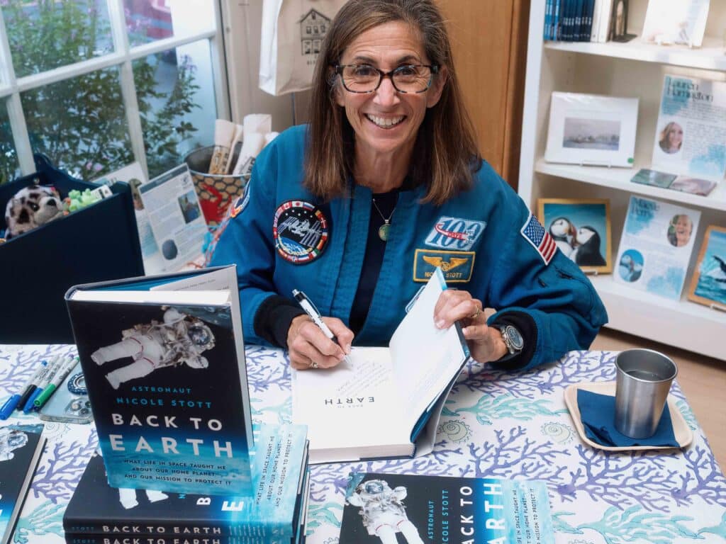 Nicole Stott smiles at the camera while signing her book at the event.